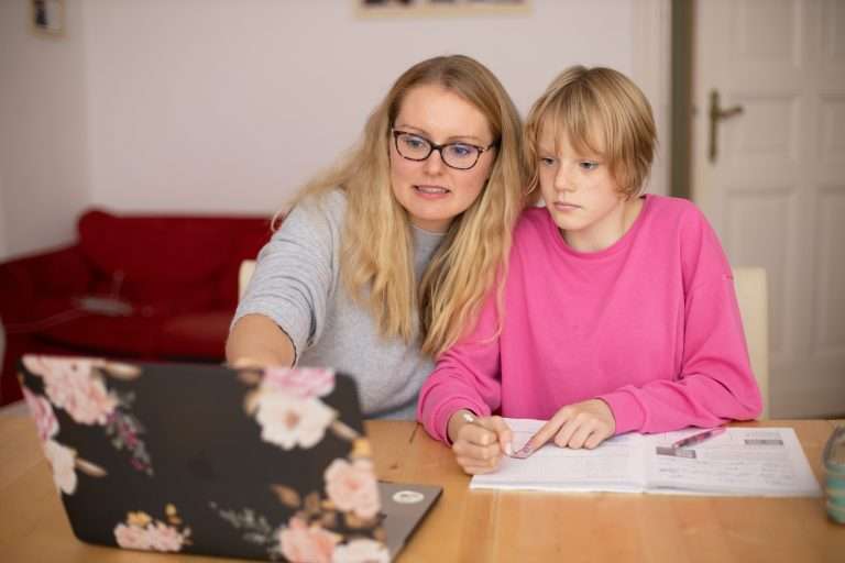 A girl in a pink shirt looks at a computer with an Orton-Gillingham tutor
